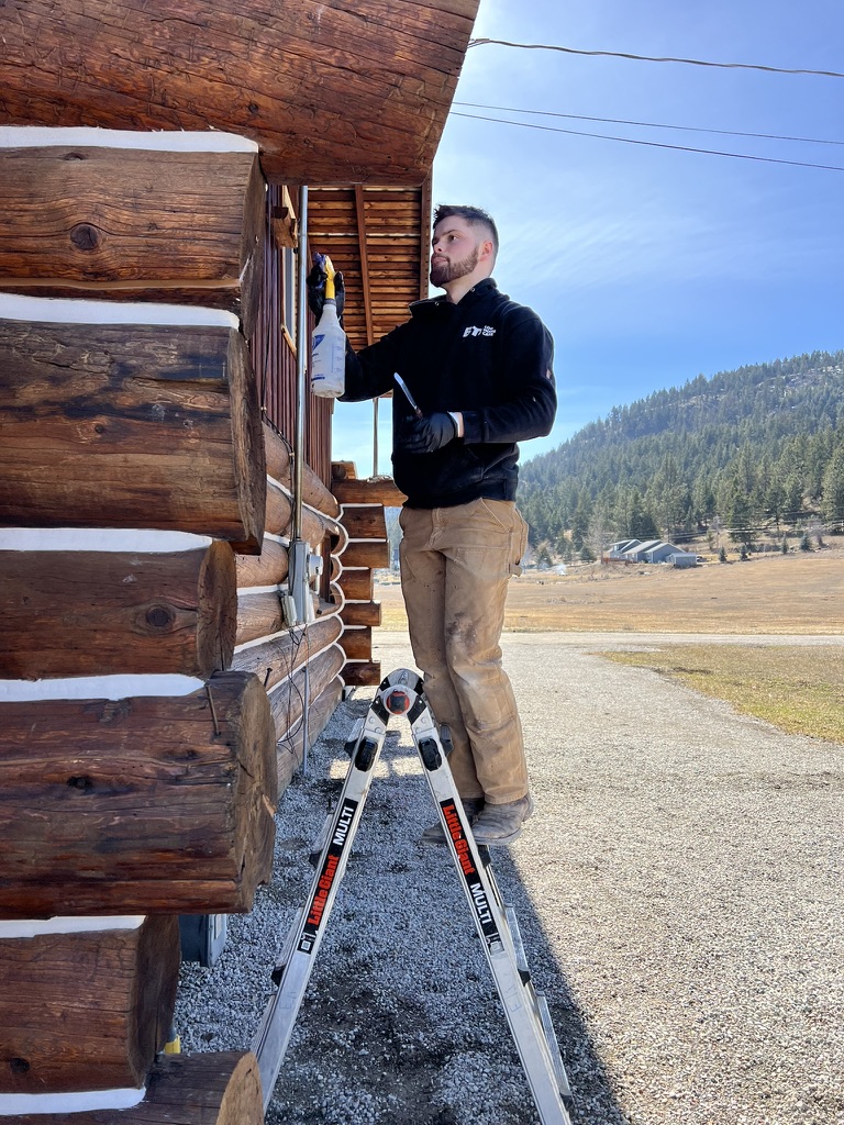 Beaver Creek crew member applying stain on ladder